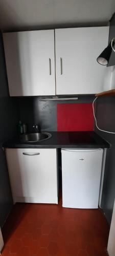 une petite cuisine avec des armoires blanches et un évier dans l'établissement Studio Rue st Martin, à Paris