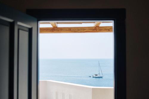 a window view of a boat in the ocean at Chrysalis Boutique - Adults Only in Astypalaia Town