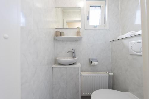 bagno bianco con lavandino e servizi igienici di MP 10 - Deichgraf 2 Komfort a Dorum-Neufeld