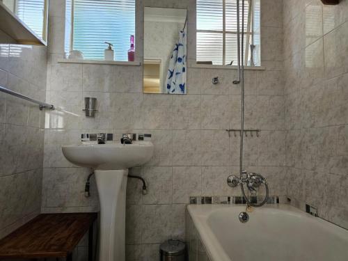 ein weißes Badezimmer mit einem Waschbecken und einer Badewanne in der Unterkunft Alberton Africa Away in Alberton