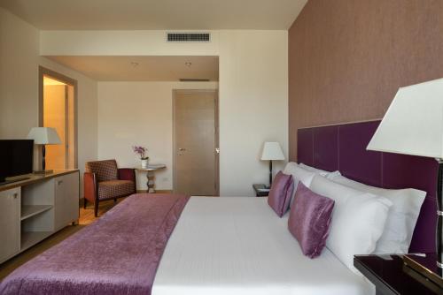 a bedroom with a large bed with a purple headboard at Hotel Nazionale in Desenzano del Garda