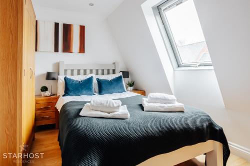 een slaapkamer met een bed met blauwe kussens en een raam bij Central 3 bed apartment at Regents Court, Newbury in Newbury