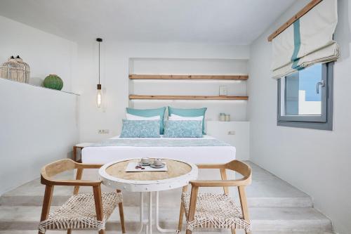 a bedroom with a bed and two chairs and a table at Chrysalis Boutique - Adults Only in Astypalaia Town