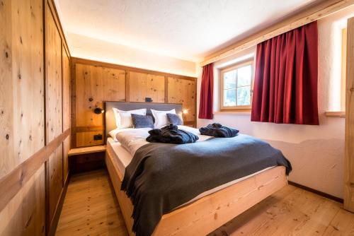 a bedroom with a large bed with a red curtain at Alm Chalet Oberkofl in San Giacomo