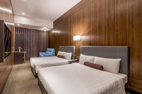 a hotel room with two beds and a blue chair at Mayer Inn in Taipei