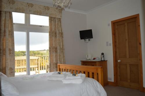 a bedroom with a bed and a window with a balcony at Strathview Lodge in Dornoch