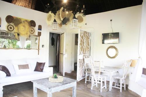 a dining room with white tables and chairs and a chandelier at Diani Beach Greenland Villa 2 Bedroom in Ukunda