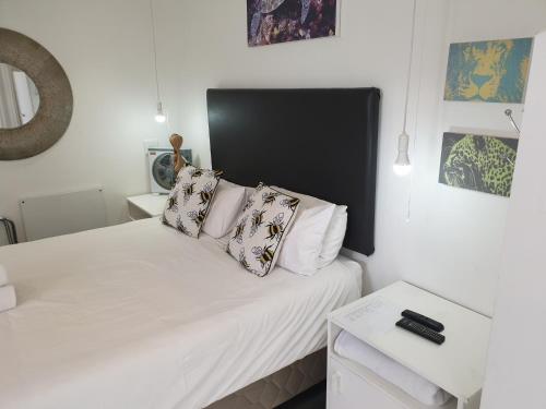 um quarto com uma cama com lençóis brancos e almofadas em 4 on Highworth Apartments and Studios na Cidade do Cabo