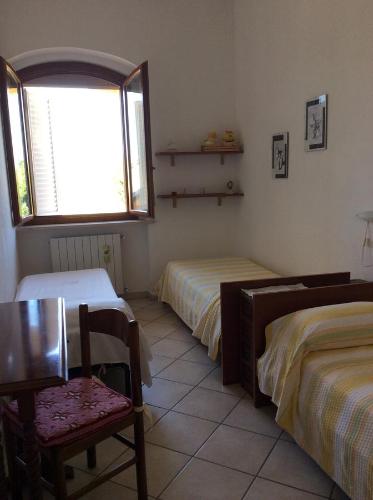 a bedroom with two beds and a chair and a window at Agriturismo Susanna e Atria in Bibbona