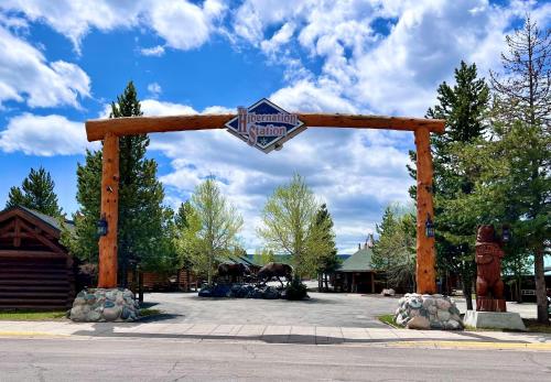 um arco de madeira com uma placa num parque de estacionamento em Hibernation Station em West Yellowstone