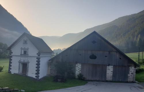 two barns with mountains in the background at Ferienwohnung Aignerhof in Schellgaden