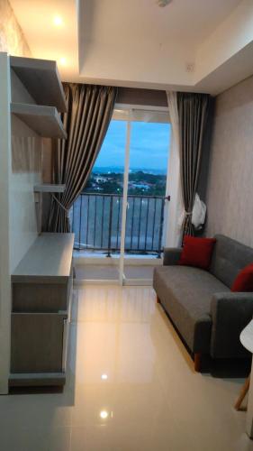 ein Wohnzimmer mit einem Sofa und einem großen Fenster in der Unterkunft Apartemen Skylounge Makassar in Sudiang