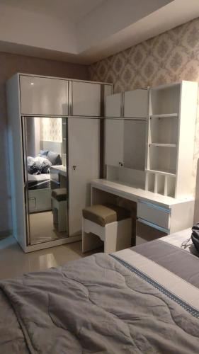 a bedroom with a bed and a desk and a mirror at Apartemen Skylounge Makassar in Sudiang