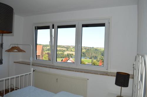 três janelas num quarto branco com vista em Gemütliches Apartment am Brombachsee mit Seeblick. em Absberg