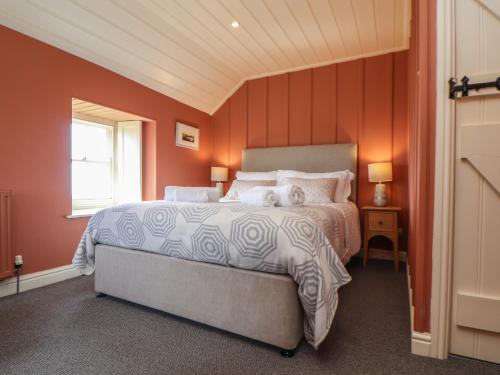 a bedroom with a large bed with orange walls at Faraway Cottage in Penzance