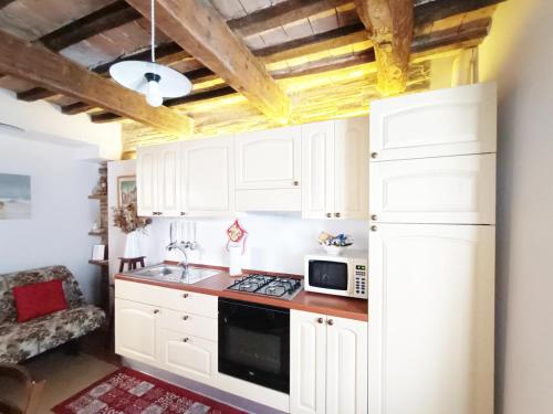 een keuken met witte kasten en een magnetron bij Casa rustica tra mare e collina in Morciano di Romagna