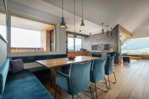 a kitchen and dining room with a wooden table and blue chairs at AlpenParks Hotel & Apartment Carpe Solem Mariapfarr in Mariapfarr