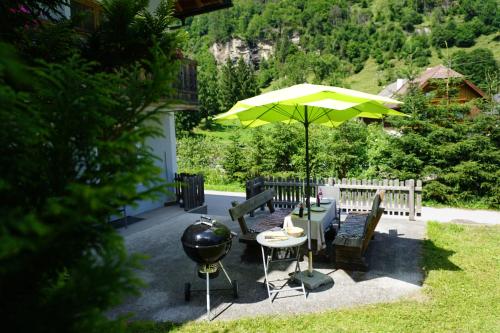 a patio with a grill and a table with an umbrella at Ferienwohnung Aignerhof in Schellgaden