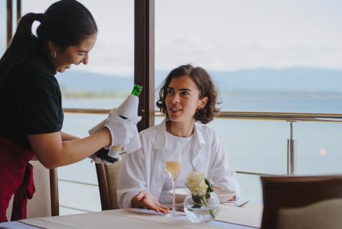 a woman sitting at a table with a glass of wine at Hotel Glamour in Kaluža