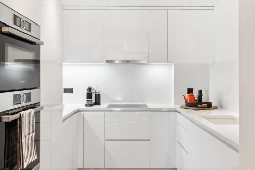 a white kitchen with a sink and a microwave at Chalet Larchwood by Mrs Miggins in Grimentz