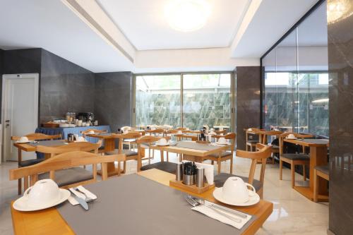 a restaurant with wooden tables and chairs and windows at Riva Hotel Alsancak in Izmir