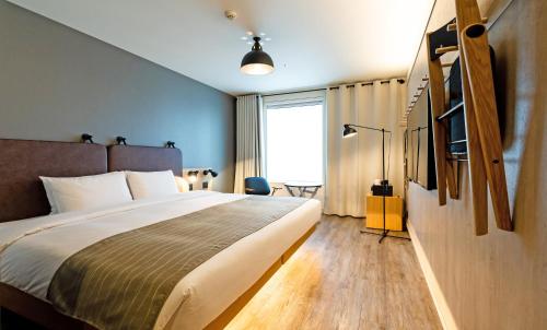 a bedroom with a large bed and a large window at MOXY Osaka Honmachi by Marriott in Osaka