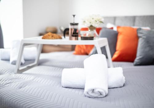 una pila de toallas en una cama con una mesa en Cosy Apartment by Klass Living Bellshill en Bellshill
