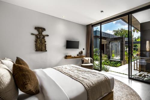 een slaapkamer met een bed en een groot raam bij Villa Jimeste by BaliSuperHost in Ubud