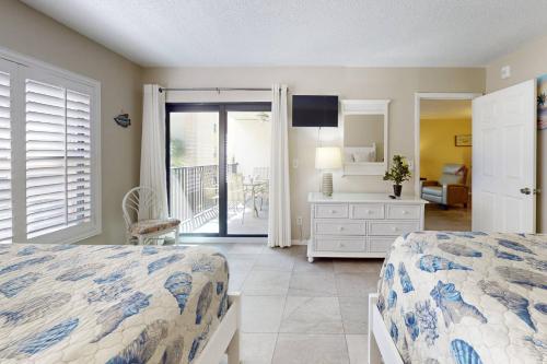 a bedroom with two beds and a balcony at 210 - Sandy Shores in St. Pete Beach