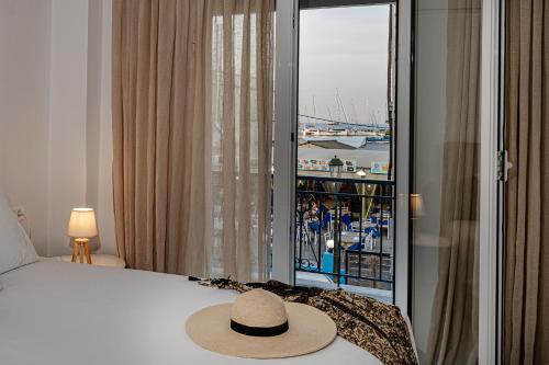 un sombrero sentado en una cama en una habitación con ventana en AMINA APARTMENTS, en Zakynthos