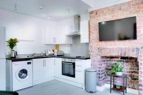 a kitchen with a brick wall with a tv on it at Modern 2 bedroom flat - 15 minutes to Liverpool in Birkenhead