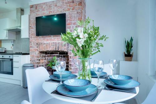 a dining room table with plates and glasses and a fireplace at Modern 2 bedroom flat - 15 minutes to Liverpool in Birkenhead