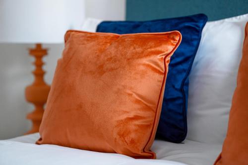 an orange pillow sitting on top of a bed at Modern 2 bedroom flat - 15 minutes to Liverpool in Birkenhead