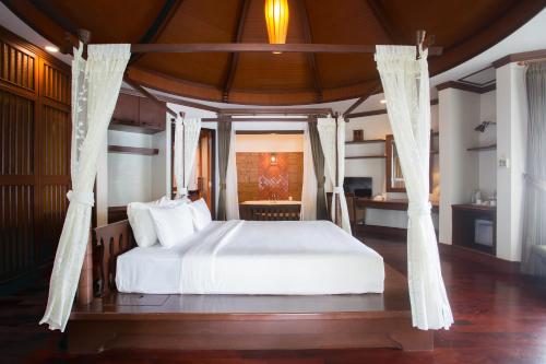 a bedroom with a bed with white sheets and curtains at Golden Beach Resort in Ao Nang Beach