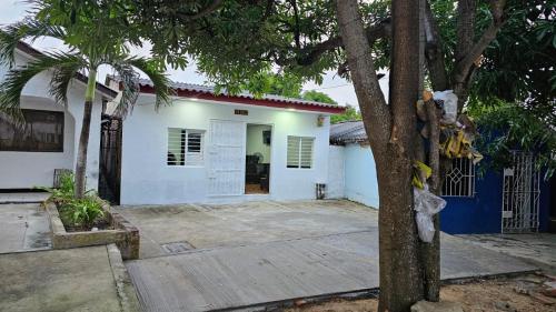 Una casa blanca con un árbol delante. en Casa familiar barranco, en Barranquilla