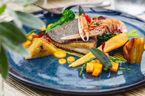 a blue plate with fish and vegetables on a table at The Salutation Inn in Topsham