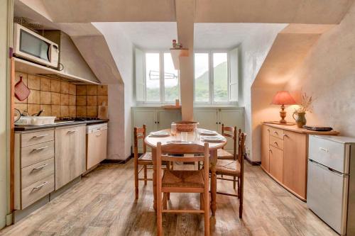 une cuisine avec une table et des chaises dans une pièce dans l'établissement Au Nid Du Gypaéte Oiseau Local, à Bedous