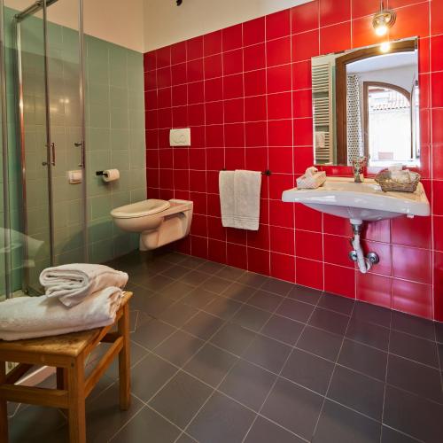 a red tiled bathroom with a sink and a toilet at Agriturismo Cascina Mirandola in Como