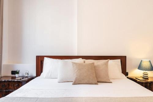 een slaapkamer met een bed met witte lakens en een lamp bij Panzeri Flexyrent Apartment Aircon e WiFi in Milaan