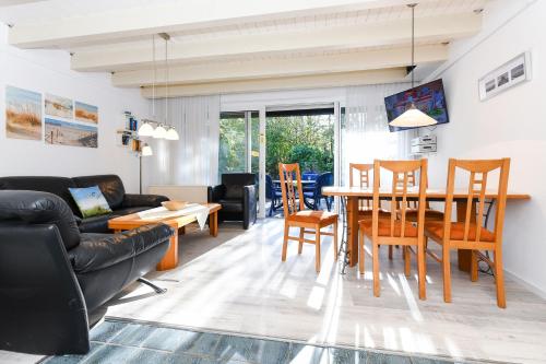 a living room with a couch and a table and chairs at Ferienhaus Deichliebe in Bensersiel