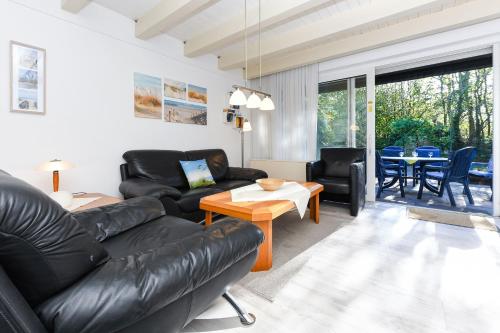 a living room with a black leather couch and a table at Ferienhaus Deichliebe in Bensersiel
