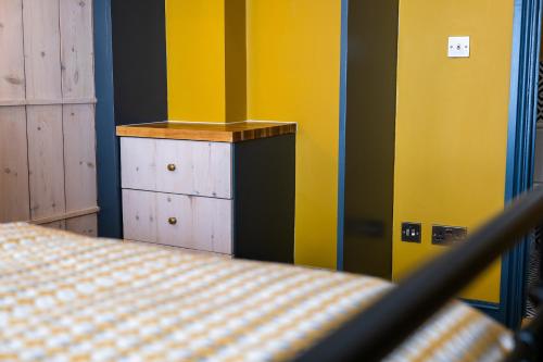 a bedroom with a bed and a yellow wall at The Sheep and Penguin in Wells
