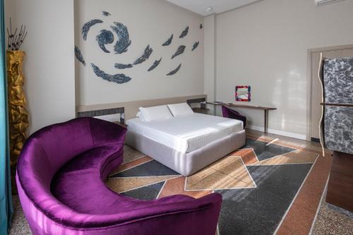 a bedroom with a bed and purple chairs at Atelier Inès Arts & Suites in Naples
