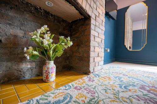 a vase of flowers sitting on a tile floor in a room at The Sheep and Penguin in Wells