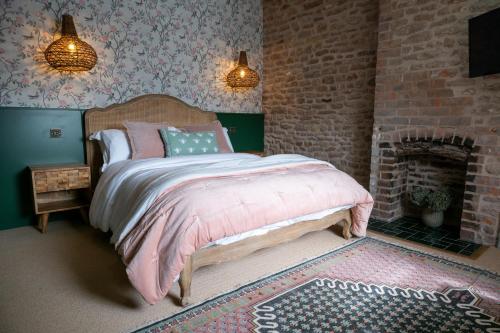 a bedroom with a bed and a brick wall at The Sheep and Penguin in Wells