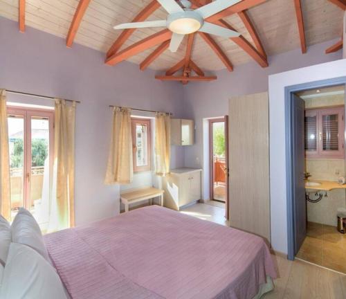 a bedroom with a pink bed and a ceiling fan at Villa Lakonia in Stoupa in Stoupa