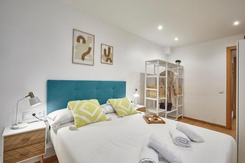 a bedroom with a large white bed with a blue headboard at BBarcelona Guinardó Flat in Barcelona
