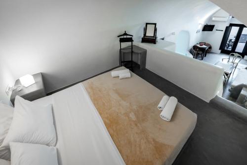 a bedroom with a white bed and a bathroom at Lotza Studios in Oia