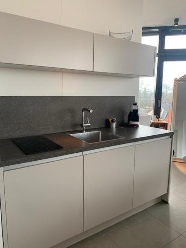a kitchen with white cabinets and a sink at Hotel im Bunker in Munich