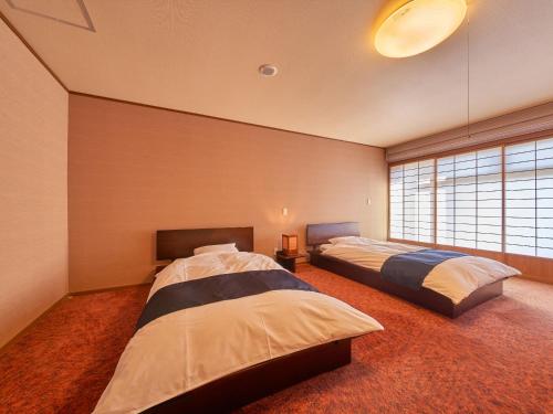 1 dormitorio con 2 camas y ventana grande en Yukai Resort Premium Ureshinokan, en Ureshino